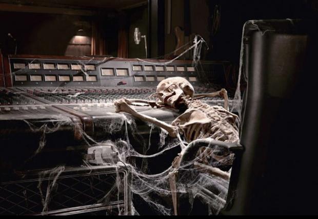 A skeleton covered in cobwebs at a mixing desk.